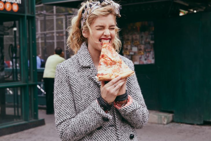 Chica mordiendo una rebanada de pizza 