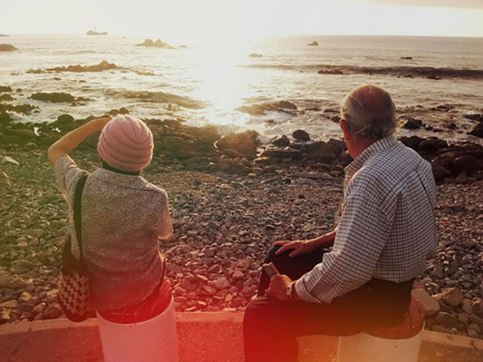 abuelo y nieta en la orilla del mar de espaldas 