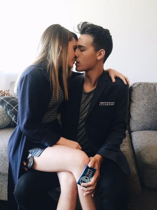 mujer sentada en las piernas de su novio lo besa 