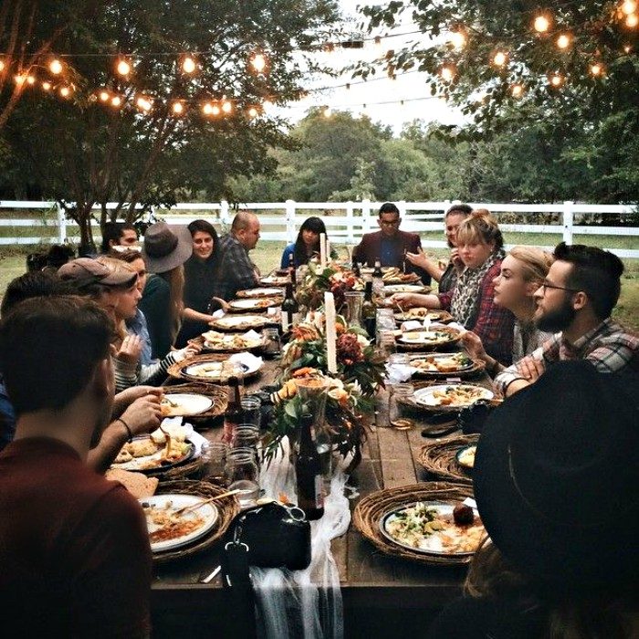 familia en comida familiar con larga mesa y luces 