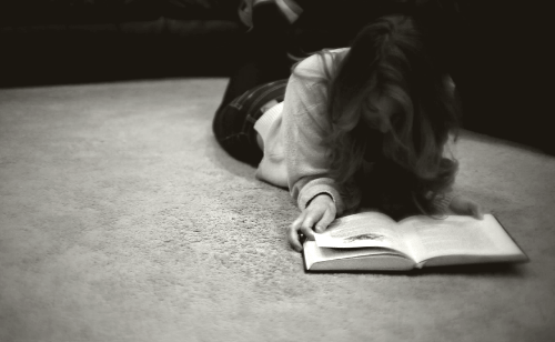 chica acostada en el suelo leyendo un libro