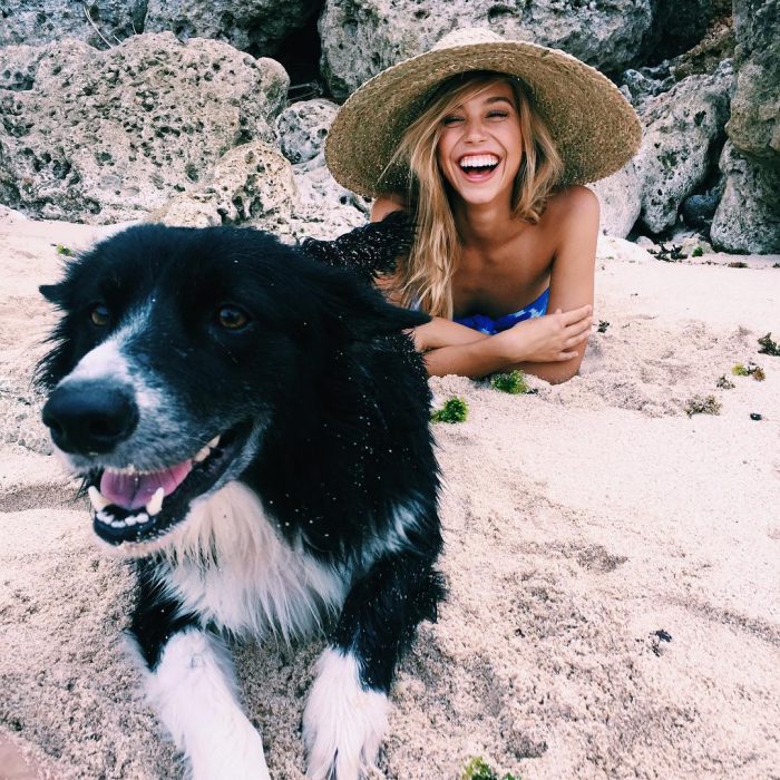 perro y muer acostada en la playa sonriendo 