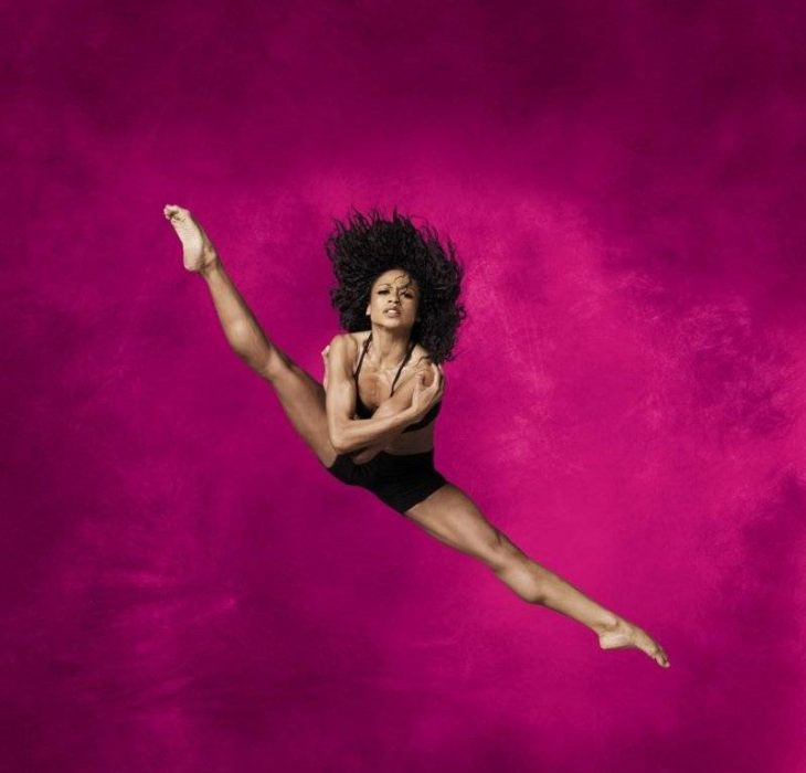 bailarina profesional salto y piernas abiertas afro rosa 