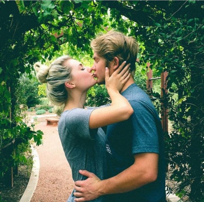 pareja de enamorados se dan un beso en un jardin