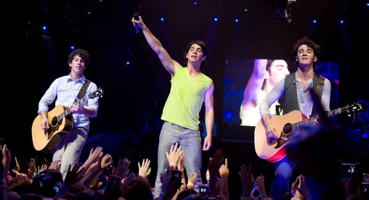 tres chicos cantando y tocando la guitarra en concierto jonas