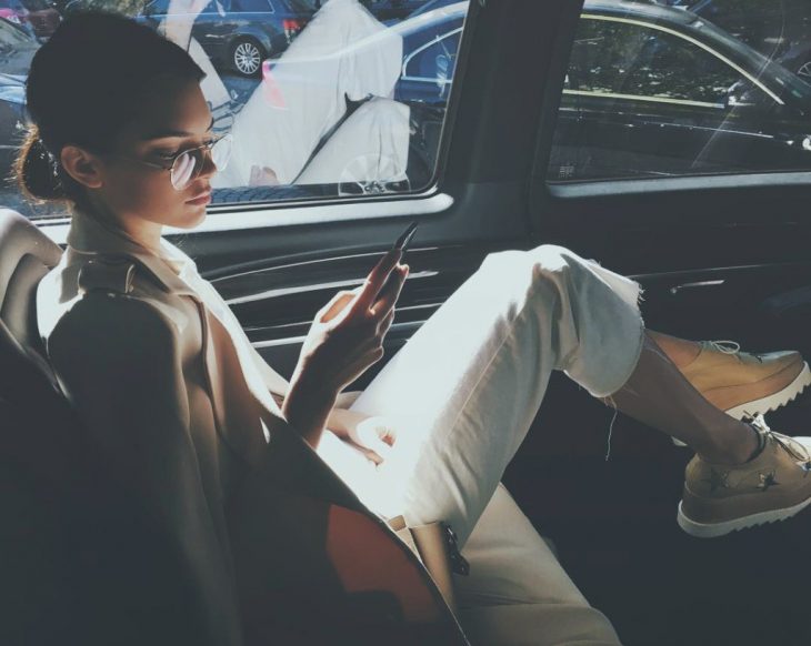 chica sentada junto a ventana de coche con su celular 