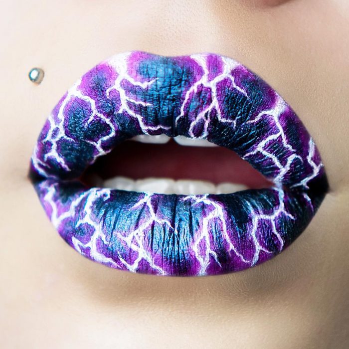 Labios pintados en tono azul con rayos en color morado 