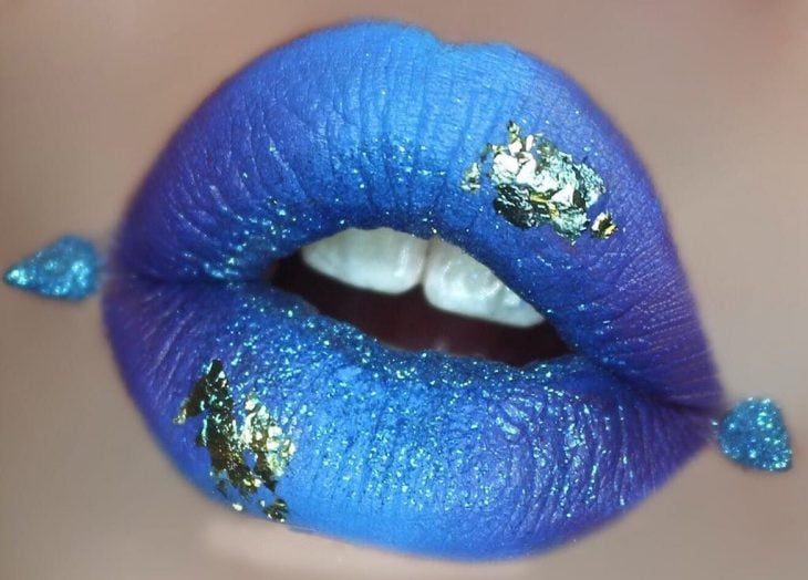 Labios de una chica pintados en color azul con toques en dorado 