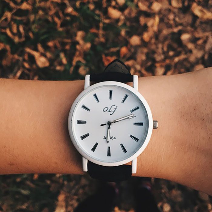 mano con reloj de mano y hojas de otoño 