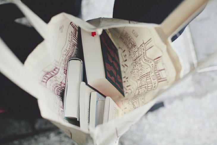 bolso blanco abierto con tres libros