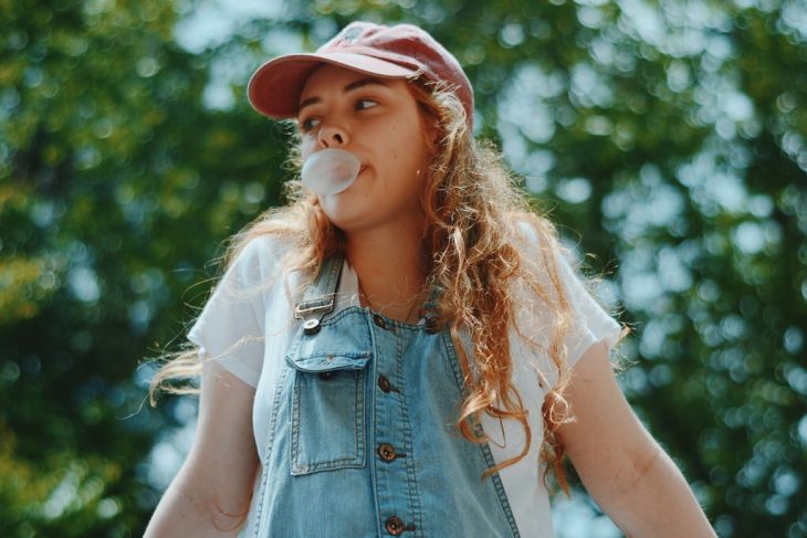 chica rubia con gorra y bomba de chicle