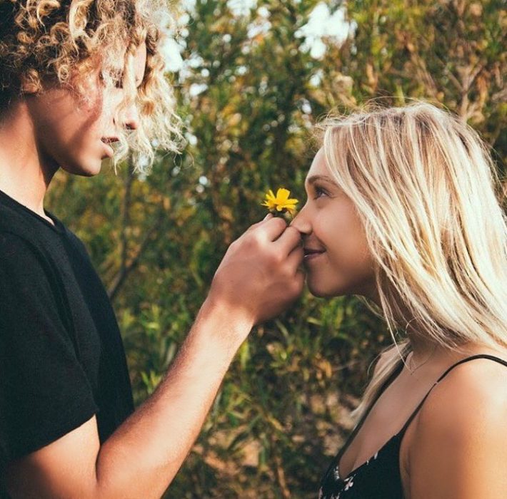 hombre y mujer de frente chico le pone flor en la nariz