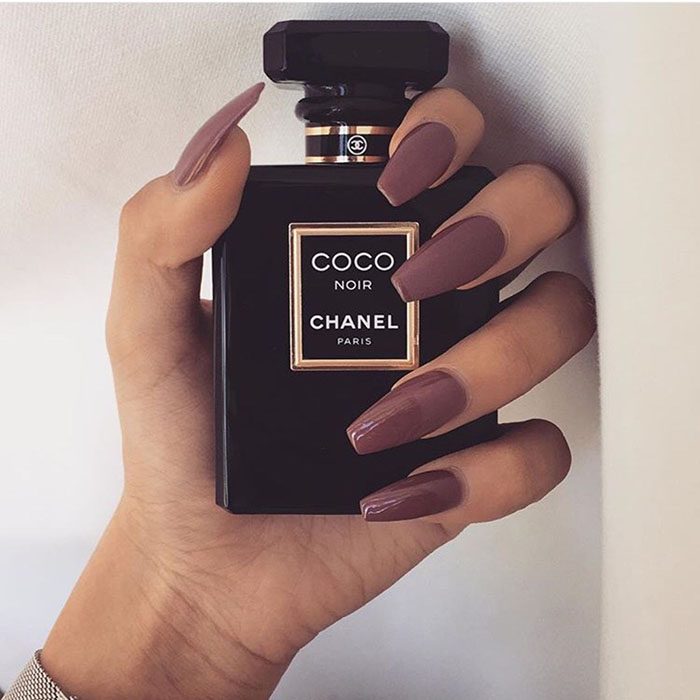 mano con esmalte cafe y perfume coco chanel 