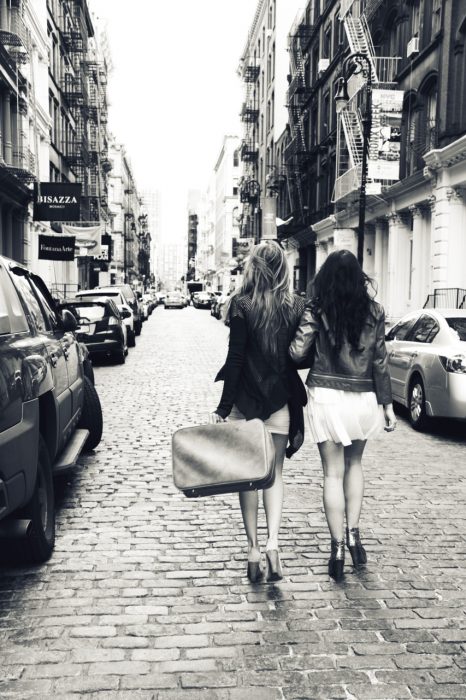 Chica con una maleta en la mano viajando junto a su mejor amiga