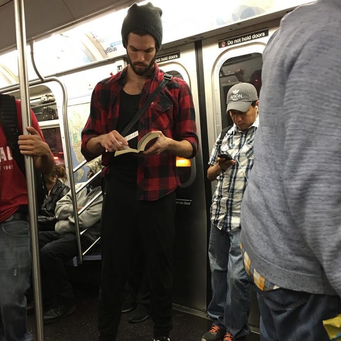 hombre de gorra y camisa de cuadros leyendo un libro 