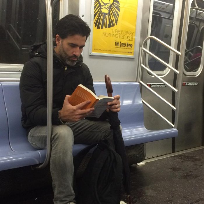 hombre con sudadera sentado leyendo un libro 