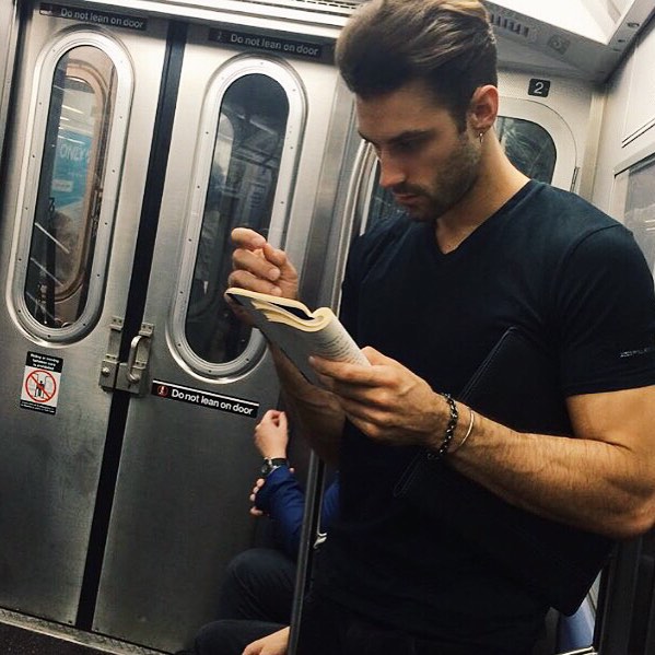 hombre de playera negra con libro leyendo en el metro 