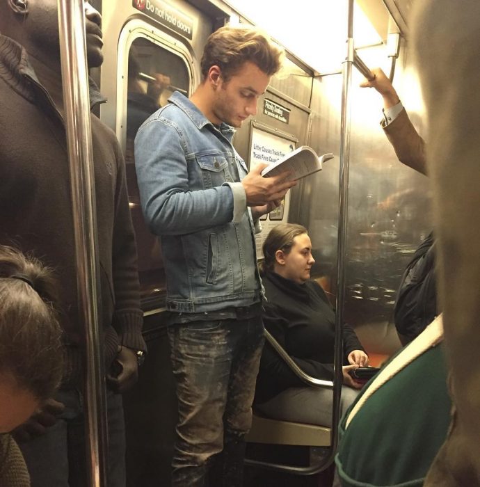 hombre rubio leyendo un libro de pie 