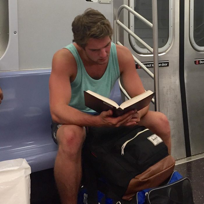 hombre con playera azul leyendo un libro 