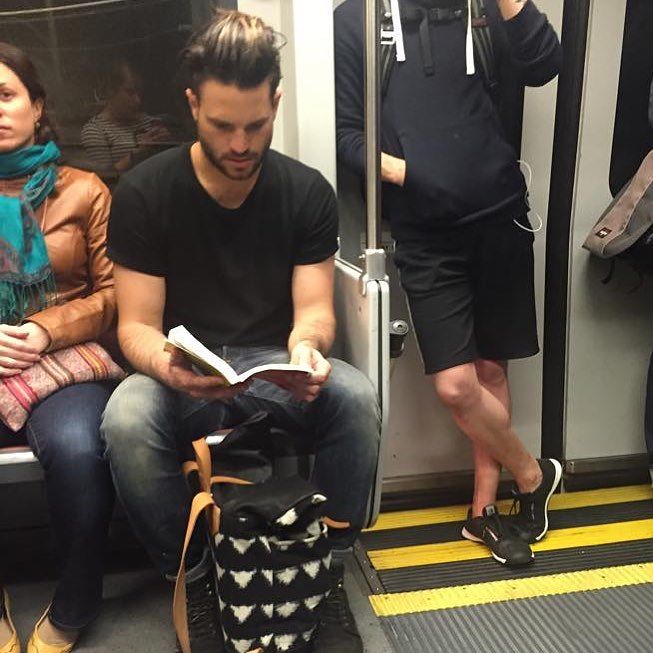 hombre de playera negra leyendo un libro en el metro 