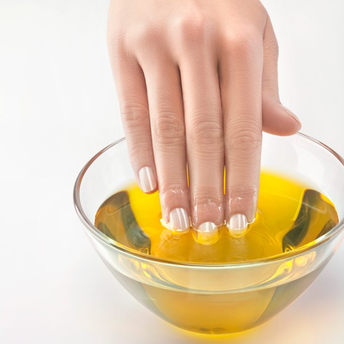 Uñas de una chica remojadas en aceite de almendras 