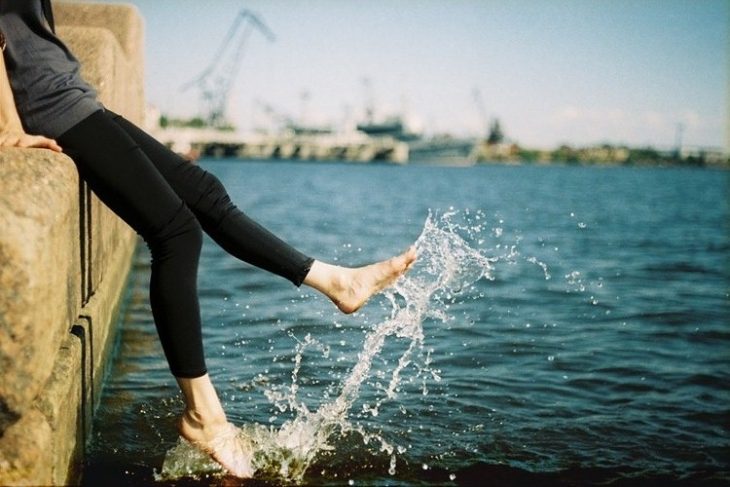 chica con los pies en el mar