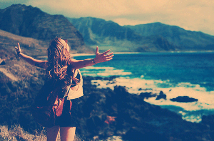 chica abriendo los brazos frente al mar