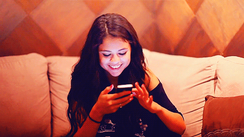 GIF Chica revisando su celular y sonriendo 