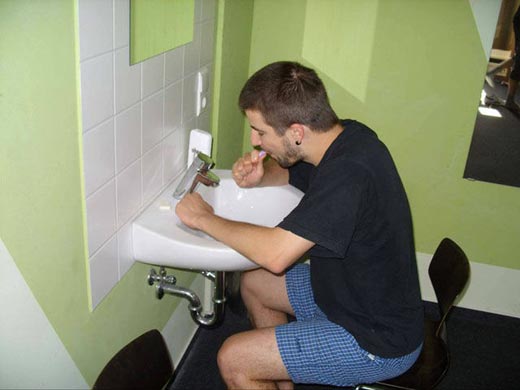 hombre lavándose los dientes sentado frente a lavabo