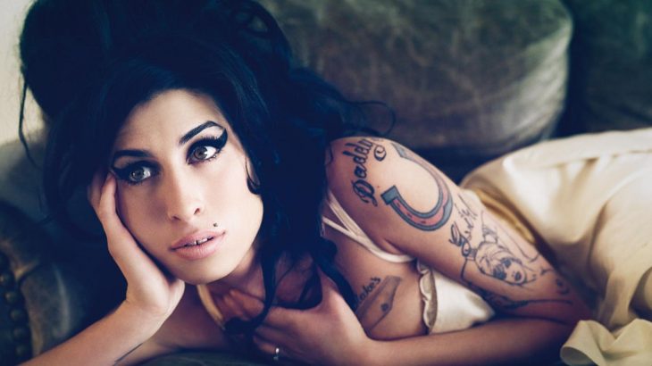 Cantante Amy Winehouse recostada en un sofá 