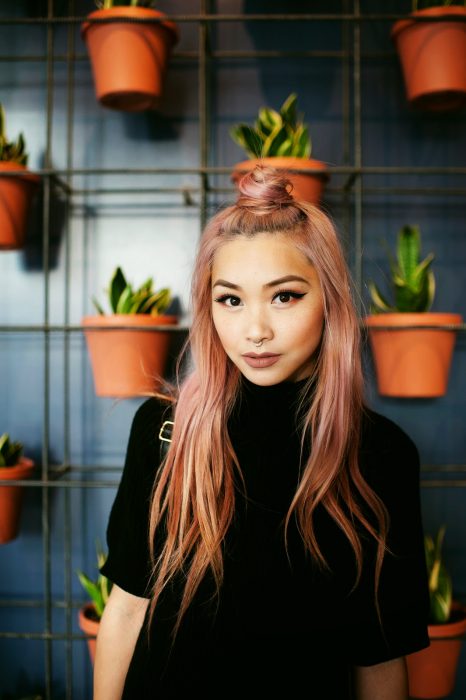 Chica con el cabello sujetado en un halfbun y pintado de color rosa-dorado 