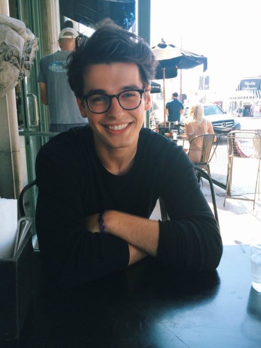 hombre lindo sonriendo con lentes en una mesa 