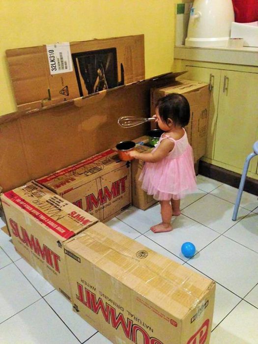 Pequeña jugando con cajas de cartón 