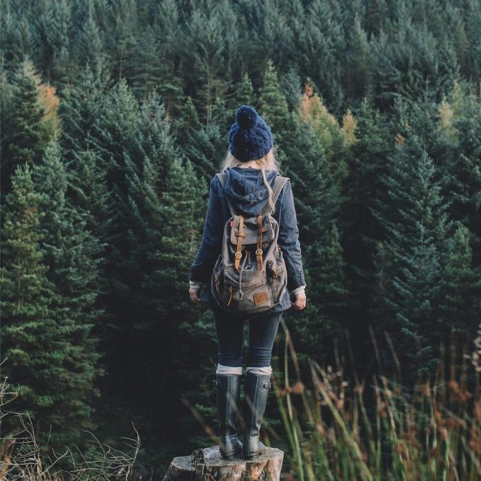 Chica parada frente a un bosque 