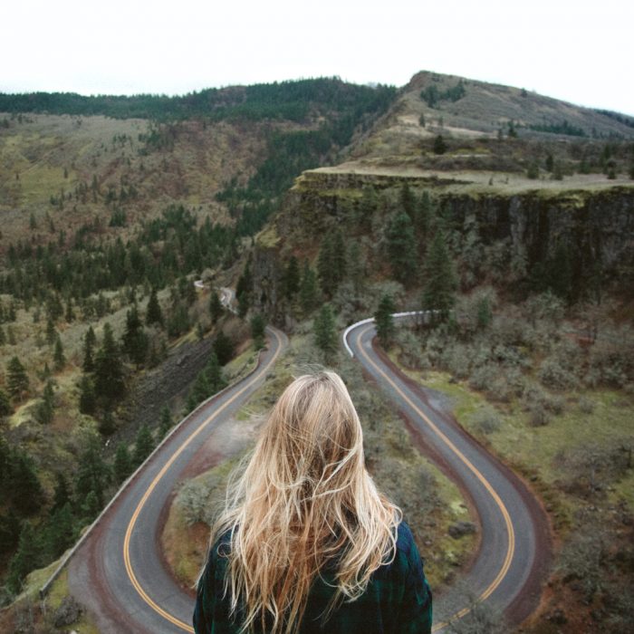 Chica en una montaña frente a una carretera 