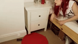 GIF chica tratando de alcanzar el control remoto del suelo desde la cama