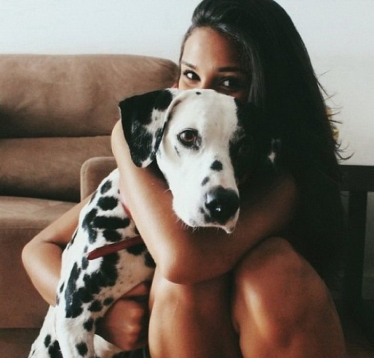 mujer abrazando a perro dalmata sentada en un sillon