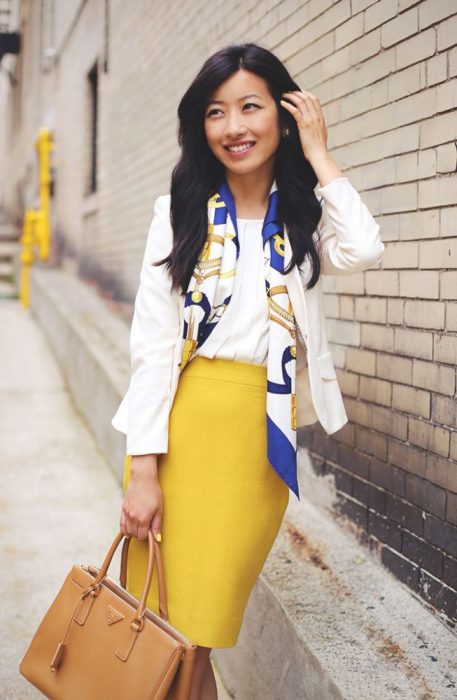 Chica usando un pañuelo con una blusa blanca y una falda amarilla 