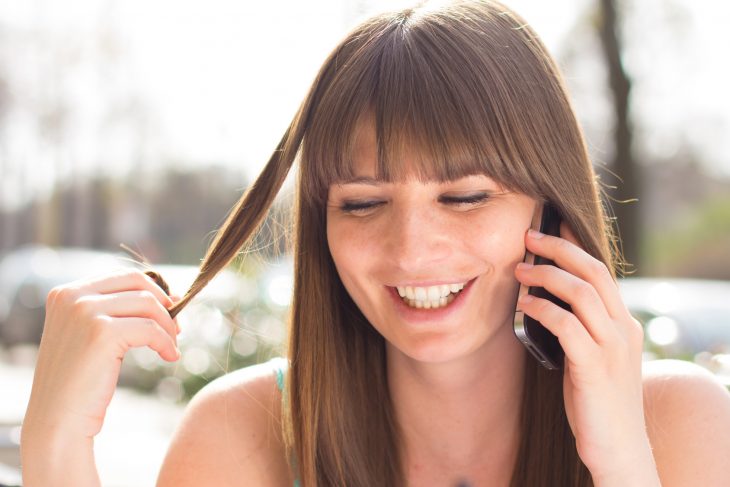 chica tocándose el cabello mientras habla por teléfono