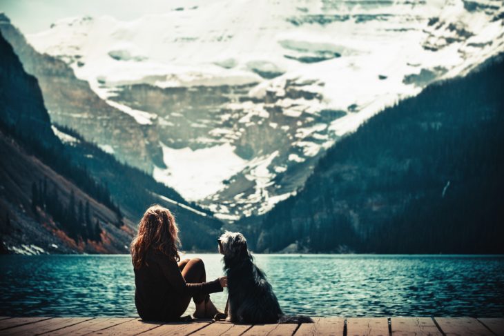 Chica a la orilla de un lago con su perro 