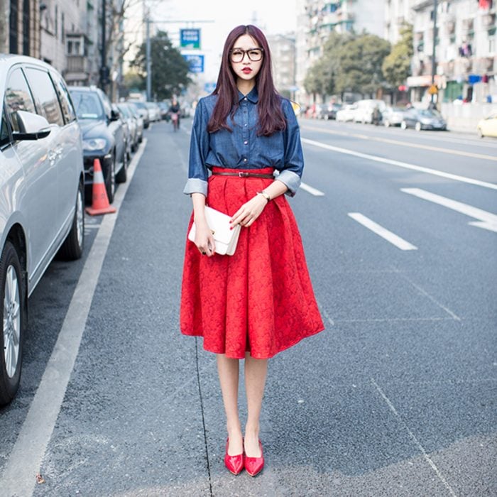 mujer en la calle con falda roja camisa azul y tacones rojo 