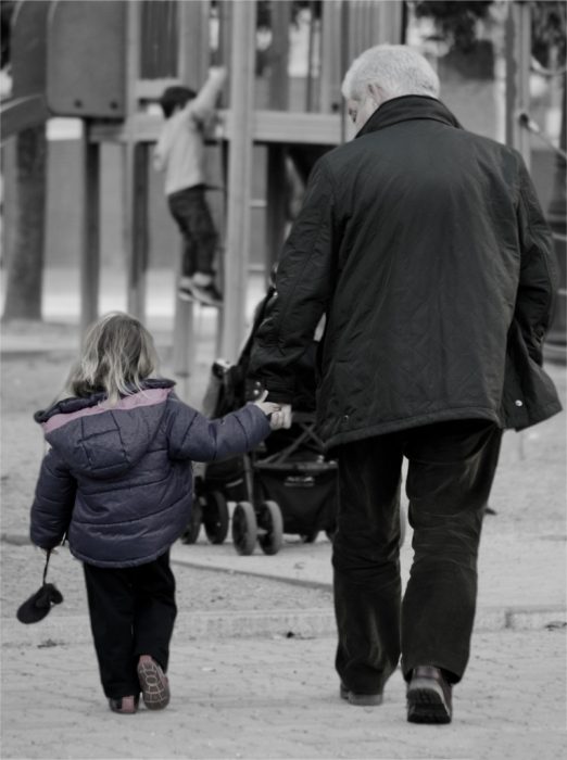 Abuelo caminando de la mano junto a su nieta 