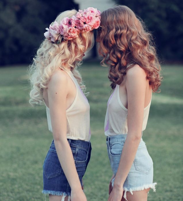 chica rubia con corona de flores en su cabeza y amiga enfrente 