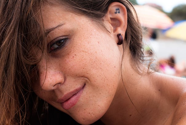 Chica con un tatuaje atrás de la oreja en forma de nota musical