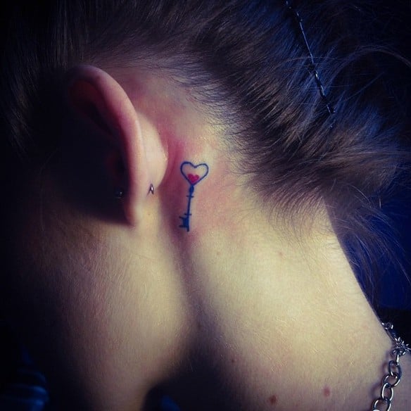 Chica con un tatuaje atrás de la oreja en forma de llave de corazón 