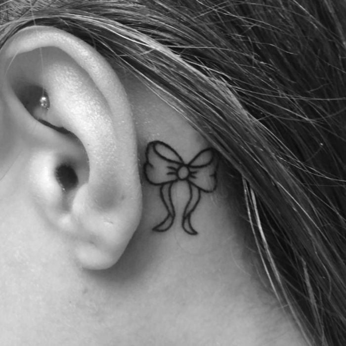 Chica con un tatuaje atrás de la oreja en forma de moño