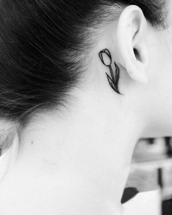 Chica con un tatuaje atrás de la oreja en forma de tulipan