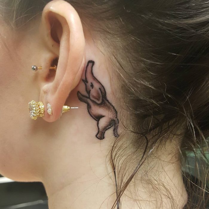 Chica con un tatuaje atrás de la oreja en forma de elefante 