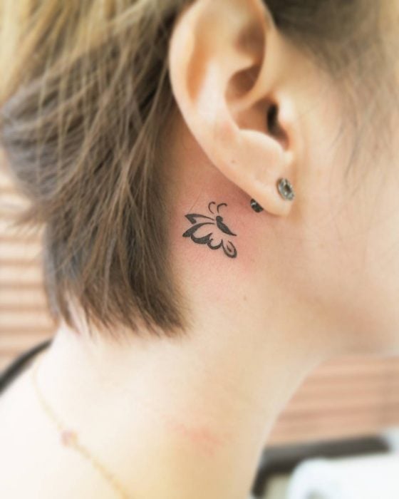 Chica con un tatuaje atrás de la oreja en forma de mariposa