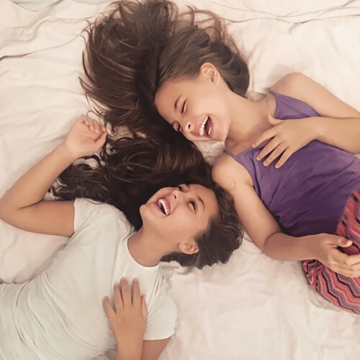 dos chicas en una cama riendo felices 